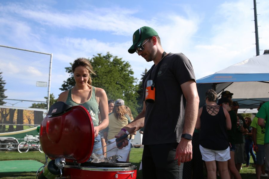Jackie Hendricks watches and waits as Kyle Rosa grills Hatch Green Chili Burgers prior to the kick off between the Rams and the Rainbow Warriors at Canvas Stadium on August 25, 2018 in Fort Collins, CO. (Elliott Jerge | Collegian).