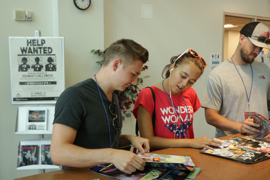 Canyon McDonald and Savannah Crosby look through all of the free comic books available at the Comic Con. (Devin Cornelius | Collegian)