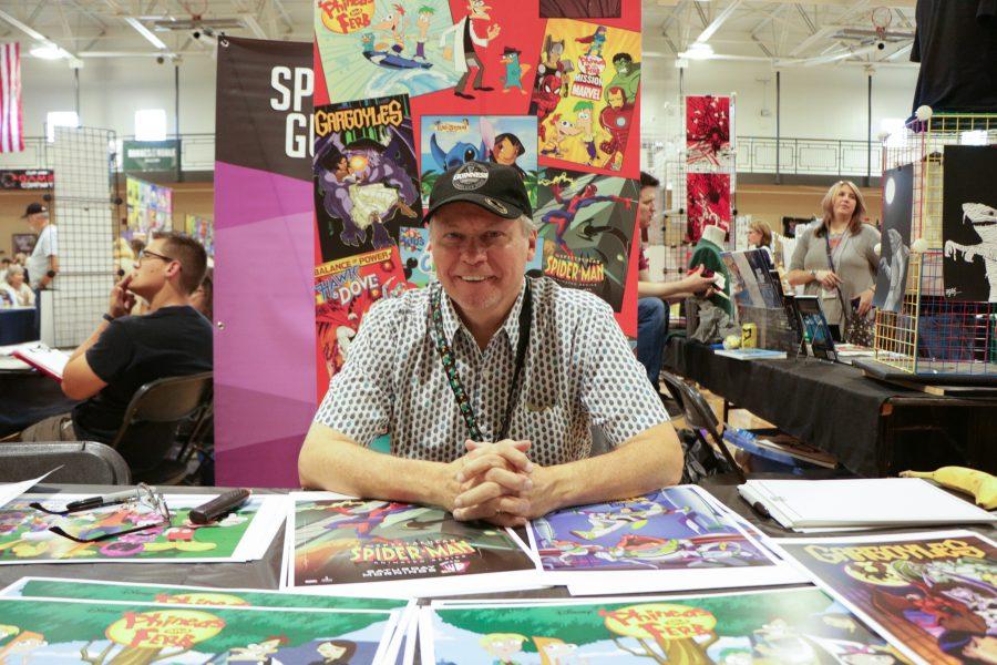 Greg Guler the artist behind Phineas and Ferb, Lilo and Stich smiles while sitting at his booth.  (Devin Cornelius | Collegian)
