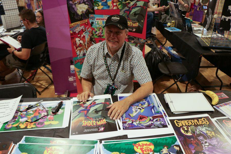 Greg Guler the artist behind Phineas and Ferb, Lilo and Stich smiles while sitting at his booth.  (Devin Cornelius | Collegian)