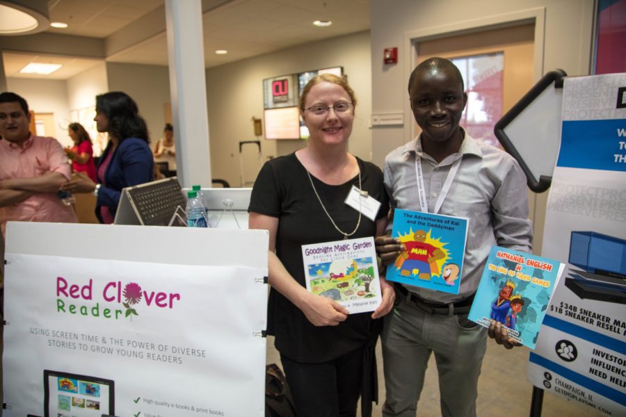 Melanie Keil and Armand Tossou, founders of Red Clover Reader, stand beside a demonstration for the children's book startup.  