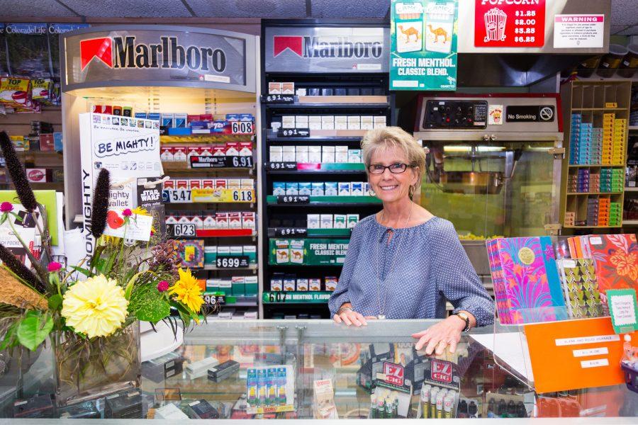 Pam Orzell, manager at Als Newsstand and Tobacco shop, stands behind the counter where she has worked for over 20 years. Pam originally worked for the wholesale distributor that supplied Als before transistioning to the retail position with the stand. (Davis Bonner | Collegian)