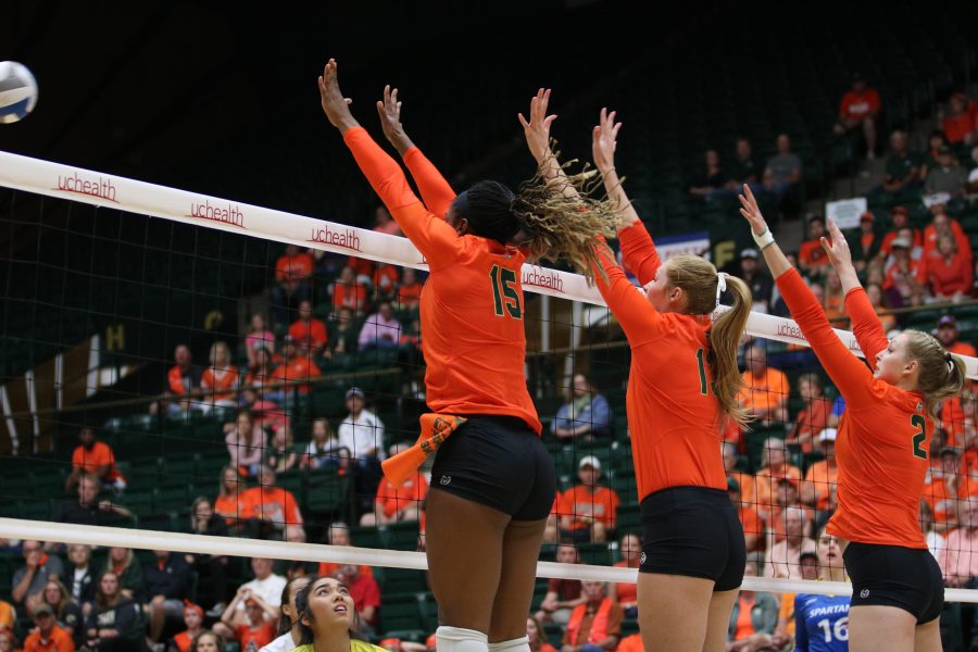 Breana Runnels (15), Kristie Hillyer (13) and Ellie Gubser (2) leap into the air to block an on coming spike. (Devin Cornelius | Collegian)