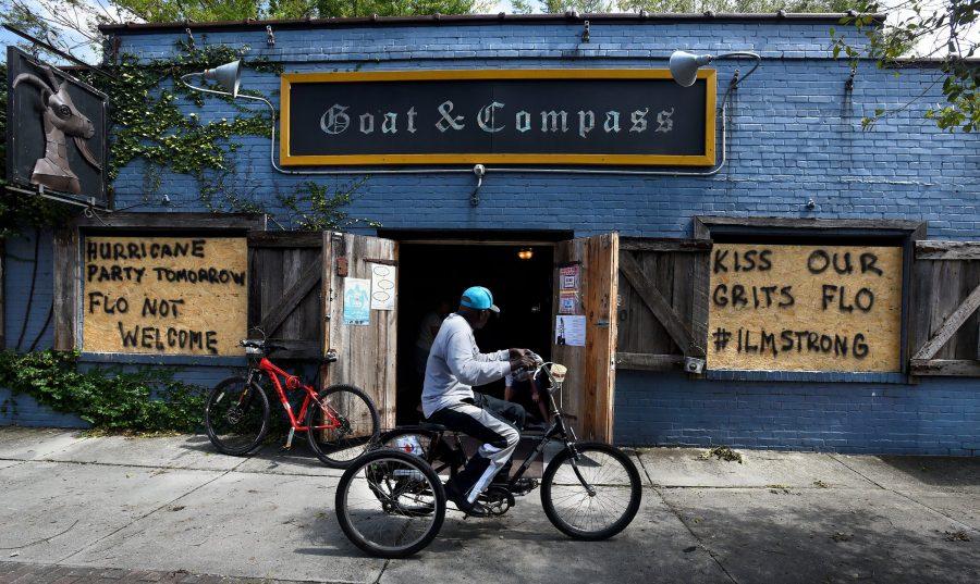 A man rides his tricycle past the open doors of the Goat & Compass bar Tuesday, Sept. 18, 2018 in Wilmington, N.C. When owner Scott Wagner found out power was restored, he thought people could use a break from their storm problems with wi-fi, phone charging stations and air conditioning. All of this and cold beverages. (Chuck Liddy/Raleigh News & Observer/TNS)