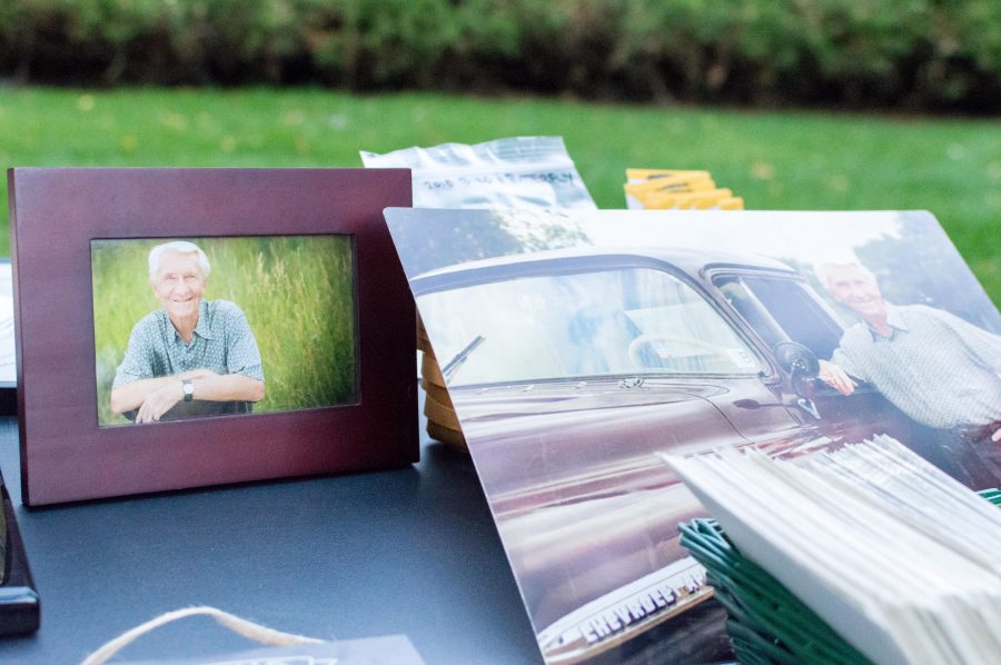 Photos of Dr. Jack Fenwick rest on a table at his celebration of life service in front of the Eastern Redbud tree planted in his honor. (AJ Frankson | Collegian)