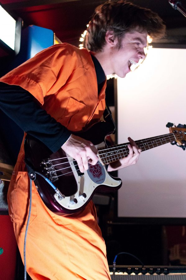 Orca Welles bassist and guitarist Alec Williams dances and plays during a show at Pinball Jones. (AJ Frankson | Collegian)