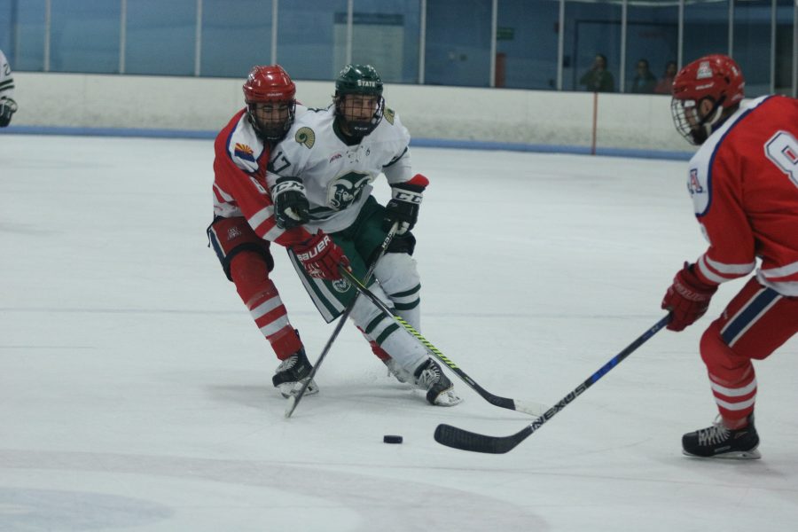 Christopher Nitchen(17) attempts to keep control of the puck as an Arizona player comes up from behind. (Devin Cornelius | Collegian)