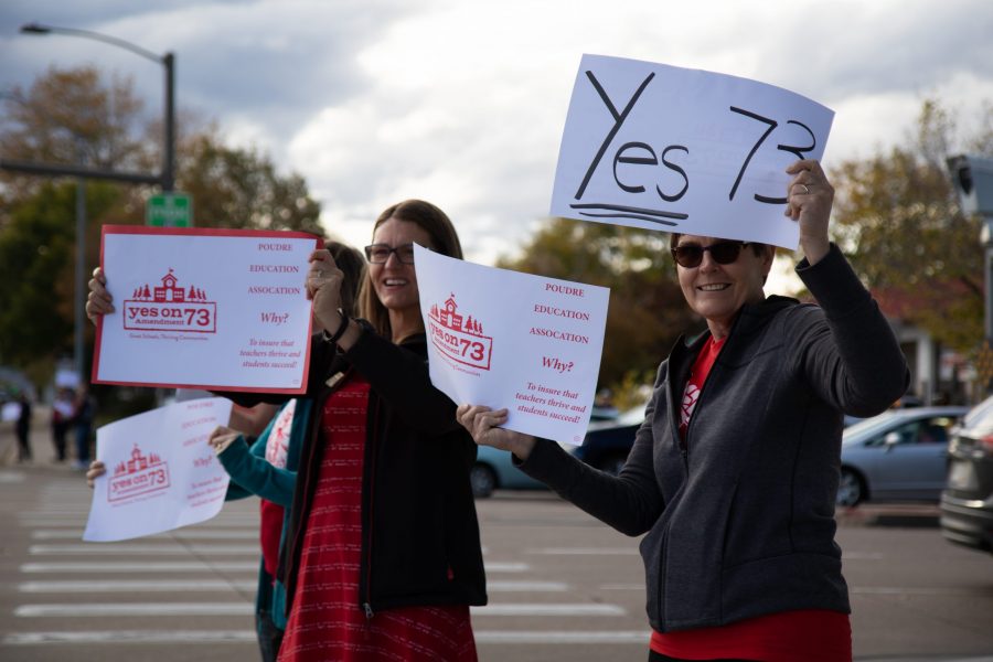 Lisa Musante, right, a teacher in the Poudre School District, and Sarah Weeks, left, who teaches in the Poudre School District, hold signs advocating for support on Amendment 73. (Julia Trowbridge | Collegian)