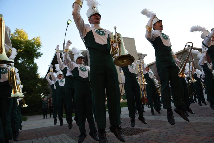 The CSU marching band jumps while playing the fight song during the homecoming parade. (Matt Tackett | Collegian)