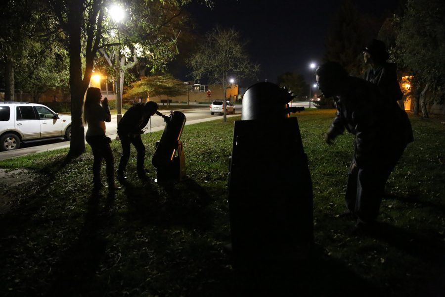 David Keller, second from left, looks at the moon through a 10-inch telescope while his girlfriend, Arianna Preuss, furthest left, watches during an open house event at the Madison-McDonald Observatory on campus on Oct. 19, 2018. (Forrest Czarnecki | Collegian)