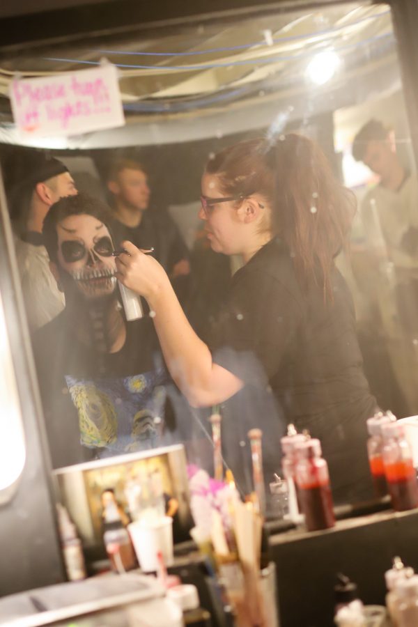 An employee in The 13th Floor Haunted House gets his makeup sprayed on before the touring of the house opens to the public. (Brooke Buchan | Collegian)