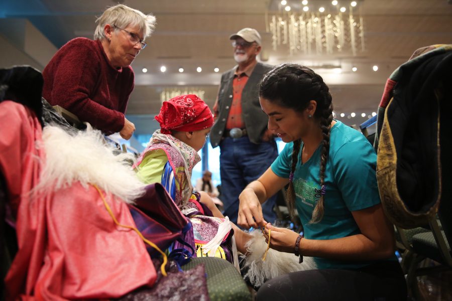 Cetan Christensen, right, helps Tate Christensen, center, get dressed in his regalia before the start of the 36th annual AISES Pow Wow at the LSC on Nov. 3, 2018.  (Forrest Czarnecki | Collegian)
