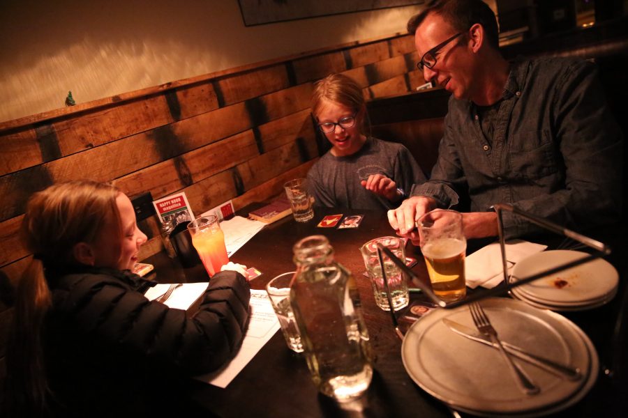 Rudy Schuster, right, and his twin daughters Claudia, left, and Anya, middle, play a game of cards while waiting for their food at Nick's Italian restaurant on Jan. 23. Schuster is employed by the United States Geologic Survey, but has been unable to work due to the federal government shutdown. Nick's was holding an event where federal employees could receive a free meal with a valid government ID. (Forrest Czarnecki | Collegian)