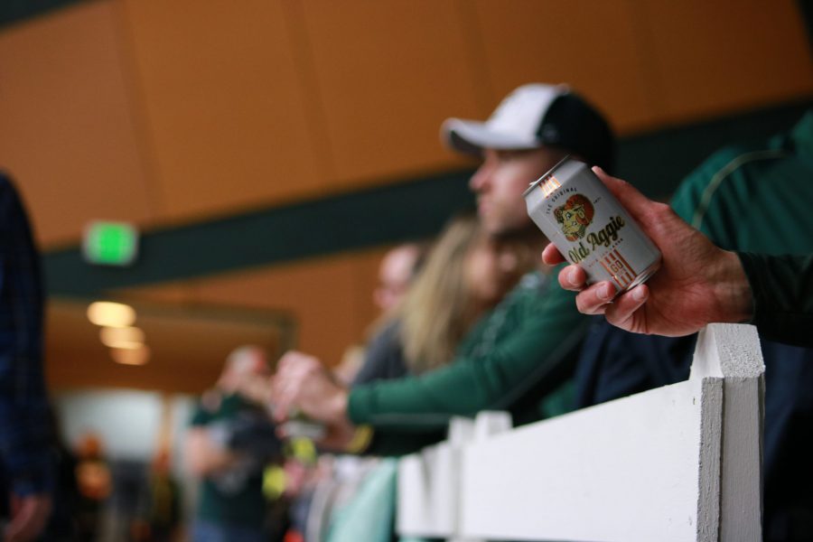A fan holds an Old Aggie can while watching a Colorado State Basketball game.