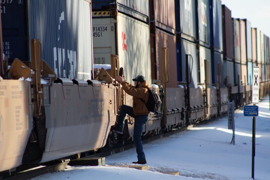 A pedestrian crosses the cars of a stopped freight train near the intersection of Mason and Laurel streets following a train and pedestrian collision at 2:57 p.m. Feb. 7. One fatality was confirmed by Fort Collins Police Services. (Austin Fleskes | Collegian)