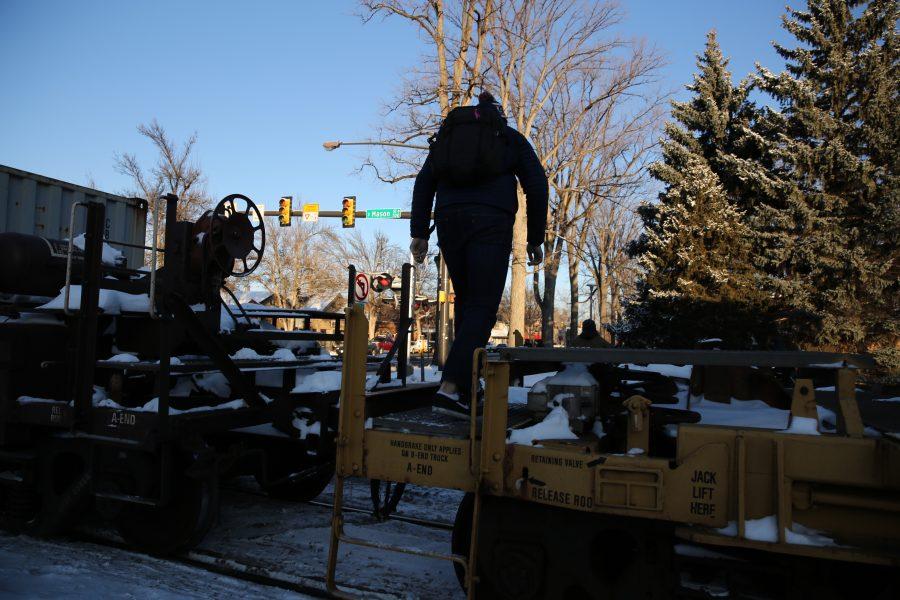Pedestrians cross in between the cars of a freight train that is stopped near the intersection of Mason and Laurel streets following a collision with a pedestrian at approximately 2:57 p.m. Feb. 7. One fatality was confirmed by Fort Collins Police Services. (Forrest Czarnecki | Collegian)