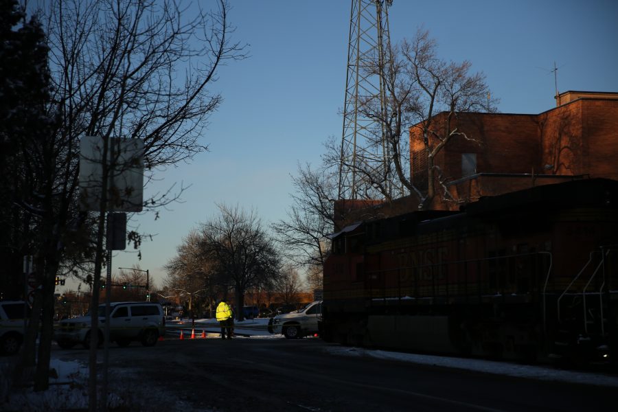 A Fort Collins Community Service Officer controls traffic in front of a stopped freight train near the intersection of Mason and Mulberry streets following a train and pedestrian collision at approximately 2:57 p.m. Feb. 7. One fatality was confirmed by Fort Collins Police Services. (Forrest Czarnecki | Collegian)