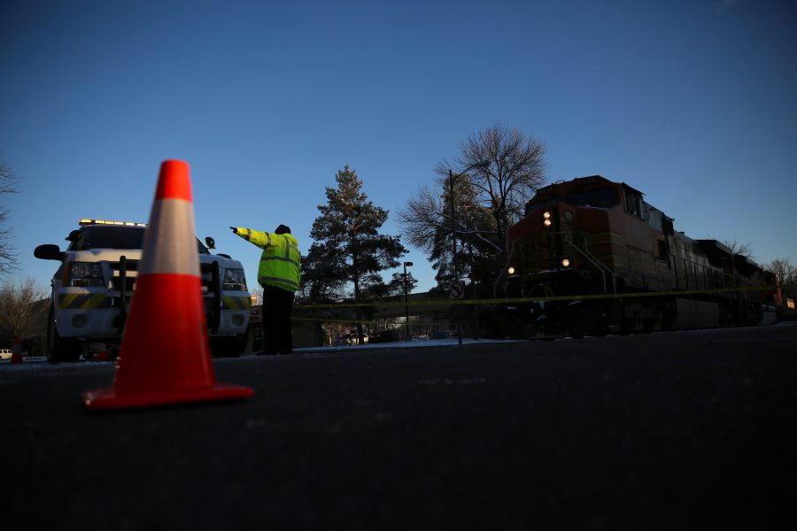 A Fort Collins Community Service Officer controls traffic in front of a stopped freight train near the intersection of Mason and Mulberry streets following a train and pedestrian collision at approximately 2:57 p.m. Feb. 7. One fatality was confirmed by Fort Collins Police Services. (Forrest Czarnecki | Collegian)