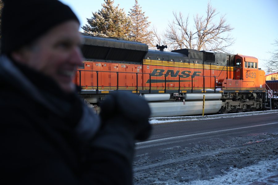 Greg Taylor clears snow from the sidewalk in front of his store while a stopped freight train sits near the intersection of Mason and Mulberry streets following a train and pedestrian collision at approximately 2:57 p.m. Feb. 7. One fatality was confirmed by Fort Collins Police Services. (Forrest Czarnecki | Collegian)