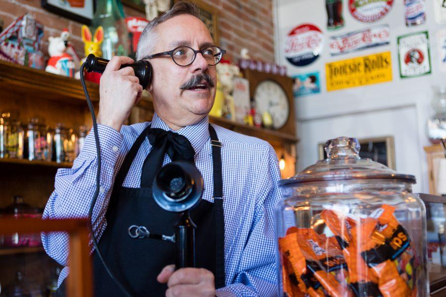 Tony Vallejos, owner of The Fort Collins Candy Store Emporium, holds an old telephone to his ear among the posters and sweets in his quirky, old-school shop. Originally from California, Vallejos is a retired interior designer who pursued his childhood dream of opening a candy store. His favorite candies are Licorice Duos, a chewy piece of licorice mixed with a fruit gummy. (Brooke Buchan | Collegian)