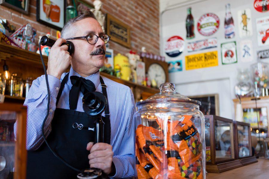 Tony Vallejos, owner of The Fort Collins Candy Store Emporium, holds an old telephone to his ear among the posters and sweets in his quirky, old-school shop. Originally from California, Vallejos is a retired interior designer who pursued his childhood dream of opening a candy store. His favorite candies are Licorice Duos, a chewy piece of licorice mixed with a fruit gummy. (Brooke Buchan | Collegian)