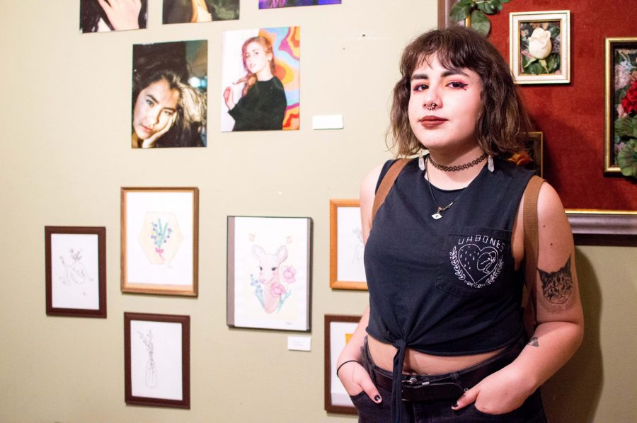 Local artist Bri Romo poses next to their art at an art show at Hotel Hillcrest on April 20, 2019. Bri regularly posts original drawings on their instagram, @brisxart, and is also in a local band called Soft Stereo. (AJ Frankson | Collegian)