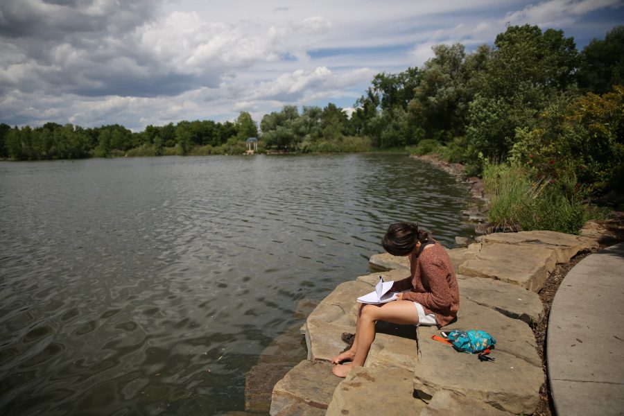 Hope Swearingen writes in a journal and soaks up the sun June 19 at City Park as temperatures climbed into the 80s and mostly sunny skies held out for the afternoon. Fort Collins is expected to see thunderstorms later in the week followed by sunny weather and temperatures back in the 80s. (Forrest Czarnecki | Collegian)