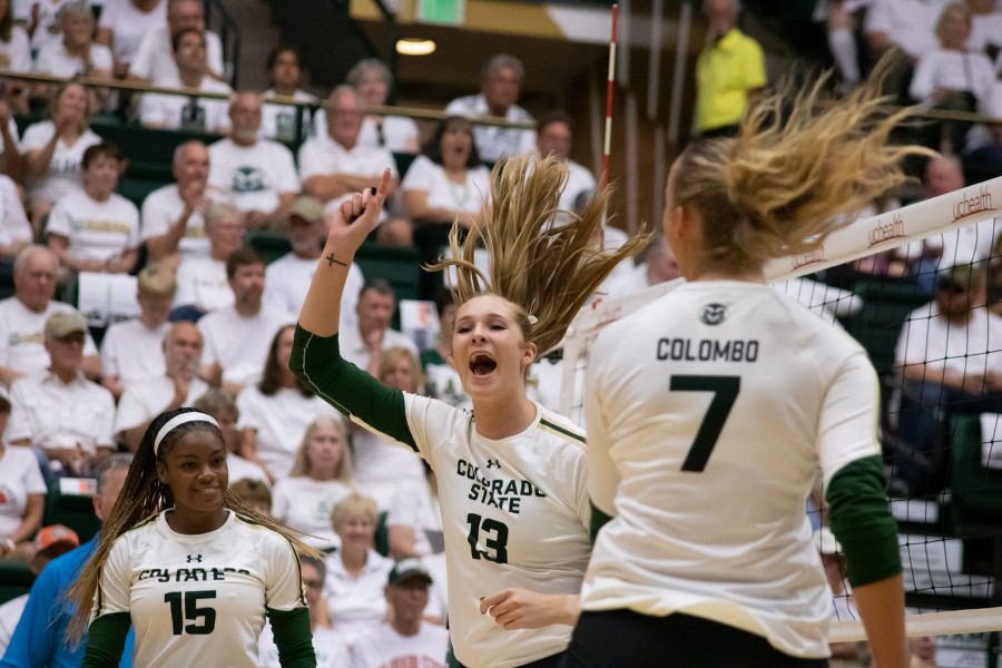 Breana Runnels (15), Kristie Hillyer (13), and Sasha Colombo (7) celebrate after scoring a point against Oklahoma University at home. The Rams beat the Sooners in the whiteout game three sets to zero.  (Devin Cornelius | Collegian)