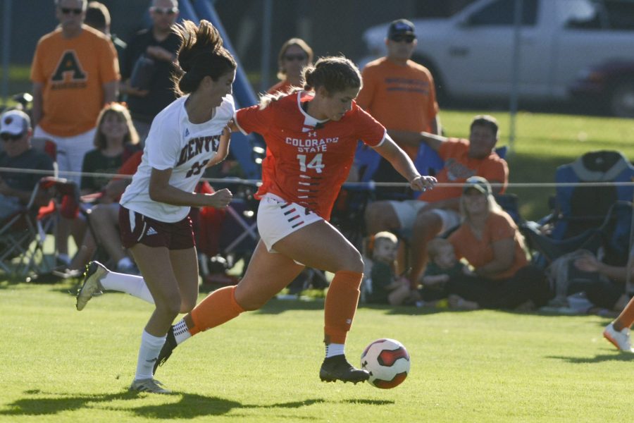 Midfielder Caeley Lordemann (14) dribbles the ball past Denver defender Hannah Adler. Lordemann had the game winning goal to make the final score 1-0 for the Rams in overtime on Sept. 13, 2019. Despite getting the game winning shot, Lordemann was quick to credit the defense as a big part of the win too. "At the end of the day, our defense stops goals," Lordemann said. "Without them we have no chance of scoring goals so they are as important as the goal itself" (Gregory James | Collegian)