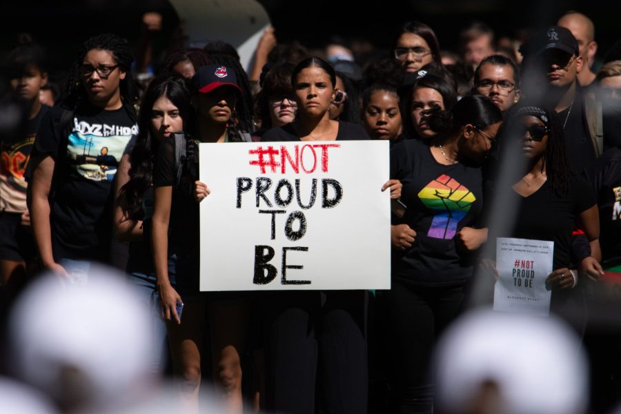 Members of the #NotProudToBe blackout event stand in front of the stage as President Joyce McConnell gives her 2019 Fall Address Sept. 19. (Matt Tackett | The Collegian)