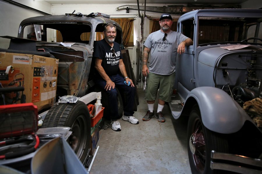 Ed Koski, left, and his son Curt Koski, right, show off a pair of cars they are in the process of restoring in their garage in northern Fort Collins. Ed Koski has been restoring cars for nearly 50 years, according to Curt Koski, including the car on the left, a rusty 1934 sedan that Curt Koski recovered from a ditch near Rapid City, South Dakota. (Forrest Czarnecki | The Collegian)
