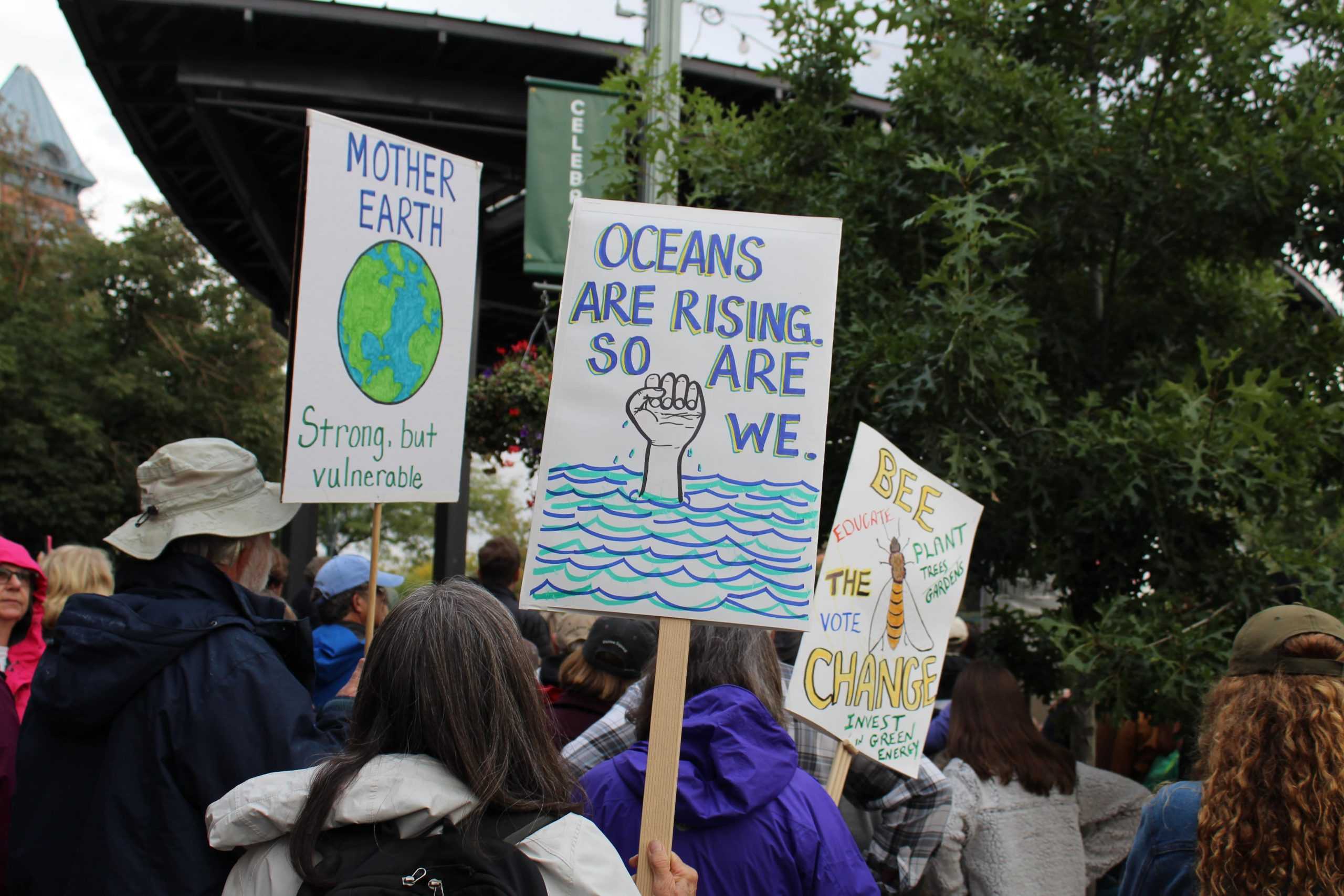 Climate change protest sign reading "OCeans are rising, so are we."