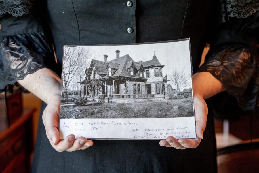 History major Morgan Iacono holds a black and white photo of the Avery House from circa 1894.  The room this photo was taken in used to be a balcony, and was later converted into another room when Frank Avery, the original owner, had more children. (Brooke Buchan | Collegian) 
