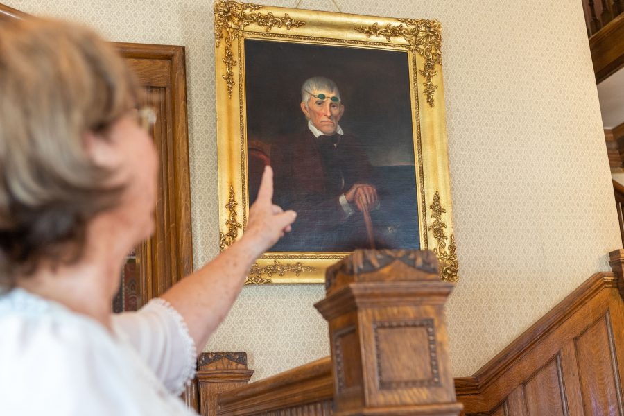 Member of the Poudre Landmark Foundation  Evelyn Reuter points to a portrait of the grandfather of Franklin Avery that hangs in the Avery House on Mountain Avenue. "People like to speculate why he wore his teal glasses over his forehead for the painting, and not over his eyes." (Brooke Buchan | Collegian)