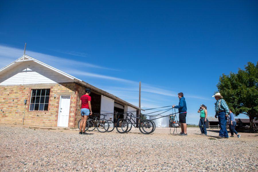 Visitors at the Centennial Bee Farm’s Pioneer Days practice using a bike-pulley system that mimics what it would be like to lead a group of horses. (Brooke Buchan | Collegian)