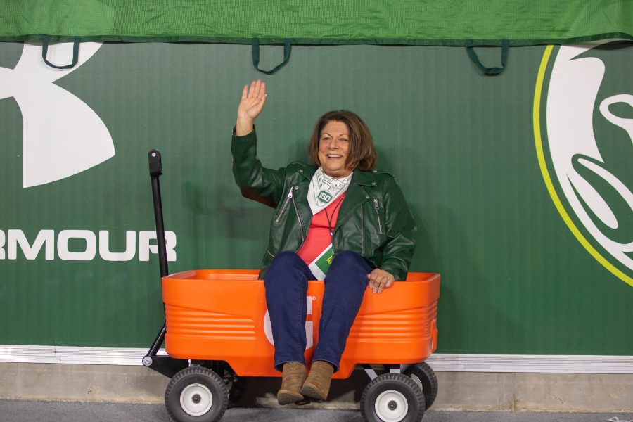 University President Joyce McConnell sits in a Gatorade wagon, smiling, and waving, during a University football game. (Devin Cornelius | Collegian)