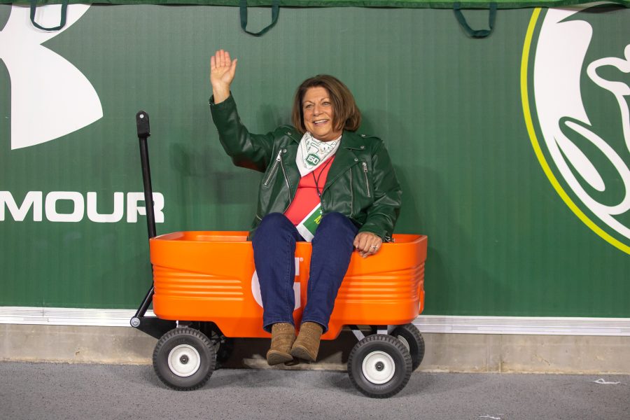 University President Joyce McConnell sits in a Gatorade wagon, smiling, and waving, during a University football game. (Devin Cornelius | Collegian)