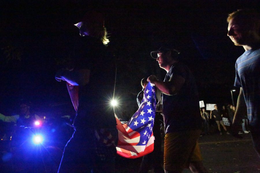 Protesters carry an American flag past the crowds at the Charlie Kirk Culture War event at the University Center for the Arts Oct. 22, 2019. The event featured both Charlie Kirk, a prominent conservative speaker, and Donald Trump Jr., where they discussed conservative values and socialism in the U.S. (Forrest Czarnecki | The Collegian)