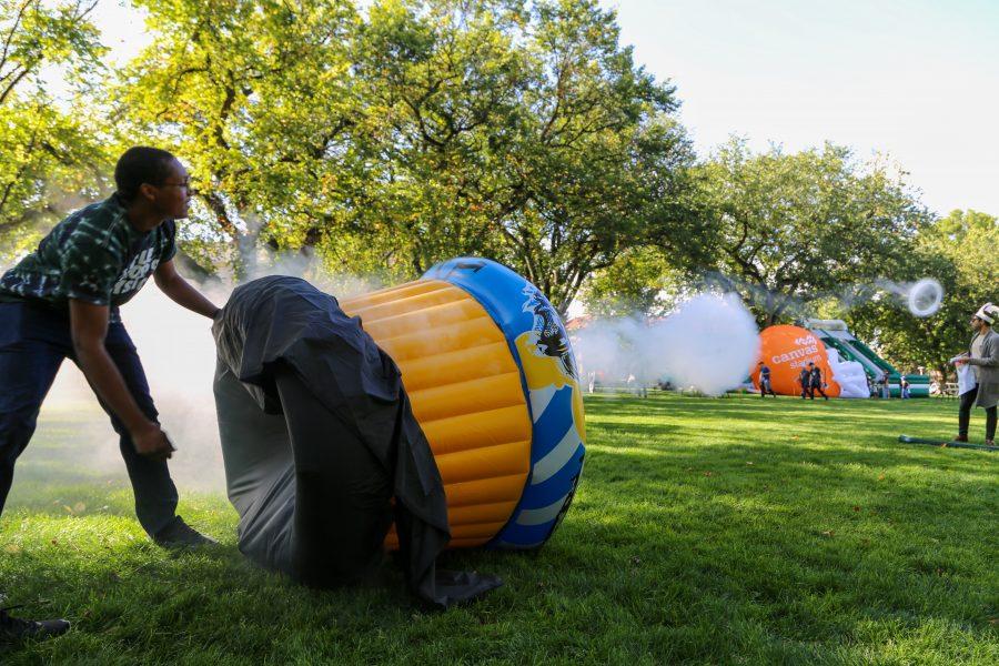 Senior Biological Sciences student and Little Shop of Physics volunteer Damar Taylor uses a handmade fogging machine to create smoke rings on the oval during homecoming weekend Friday, Oct. 4th. (Brooke Buchan | Collegian) 