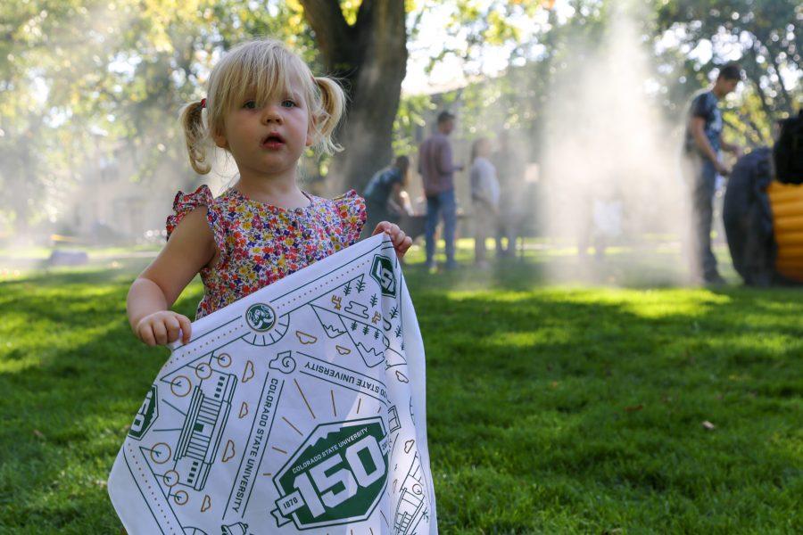 Youngster Leila H. holds up a homecoming flag on the Colorado State University oval on Friday, Oct. 4th. (Brooke Buchan | Collegian)