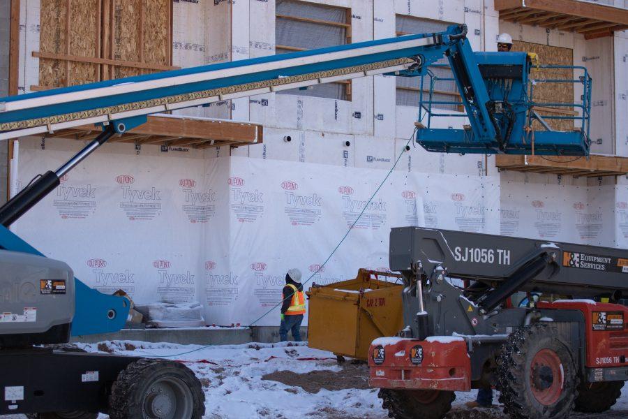 Two Construction workers as they work on a building on Lake Street, one inspects the building while the other operates a Boom Lift, on November 12th. (Devin Cornelius | Collegian)