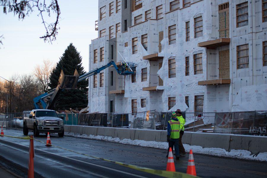 Two workers walk down the street next to a building under construction, on Lake Street. (Devin Cornelius | Collegian)