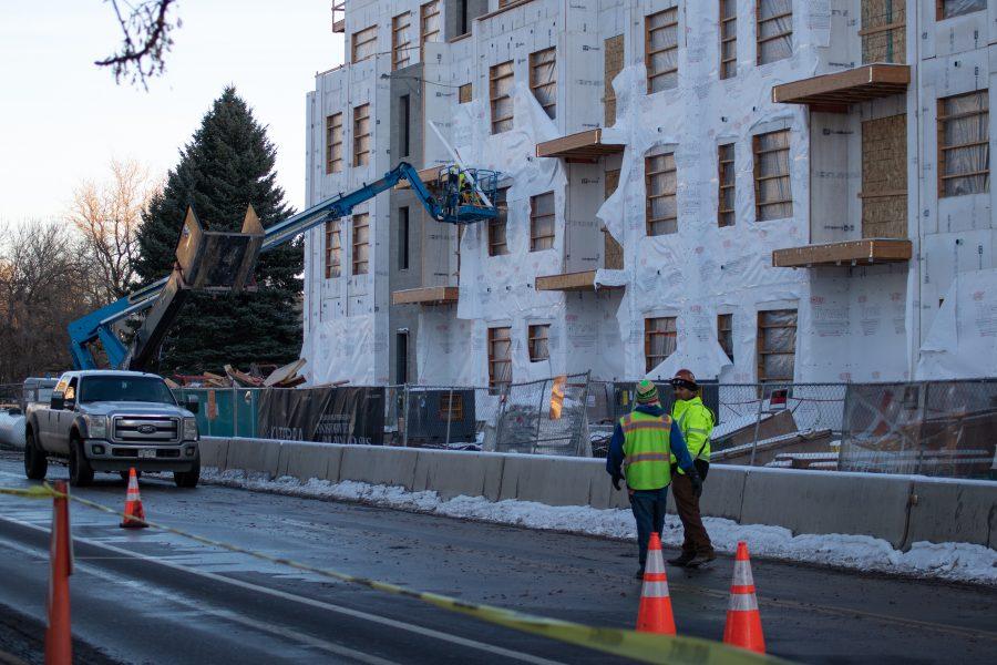 Two workers walk down the street next to a building under construction, on Lake Street. (Devin Cornelius | Collegian)
