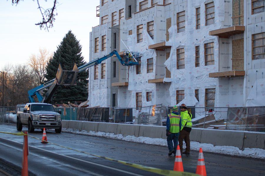 Two workers walk down the street next to a building under construction, on Lake Street. (Devin Cornelius | Collegian)