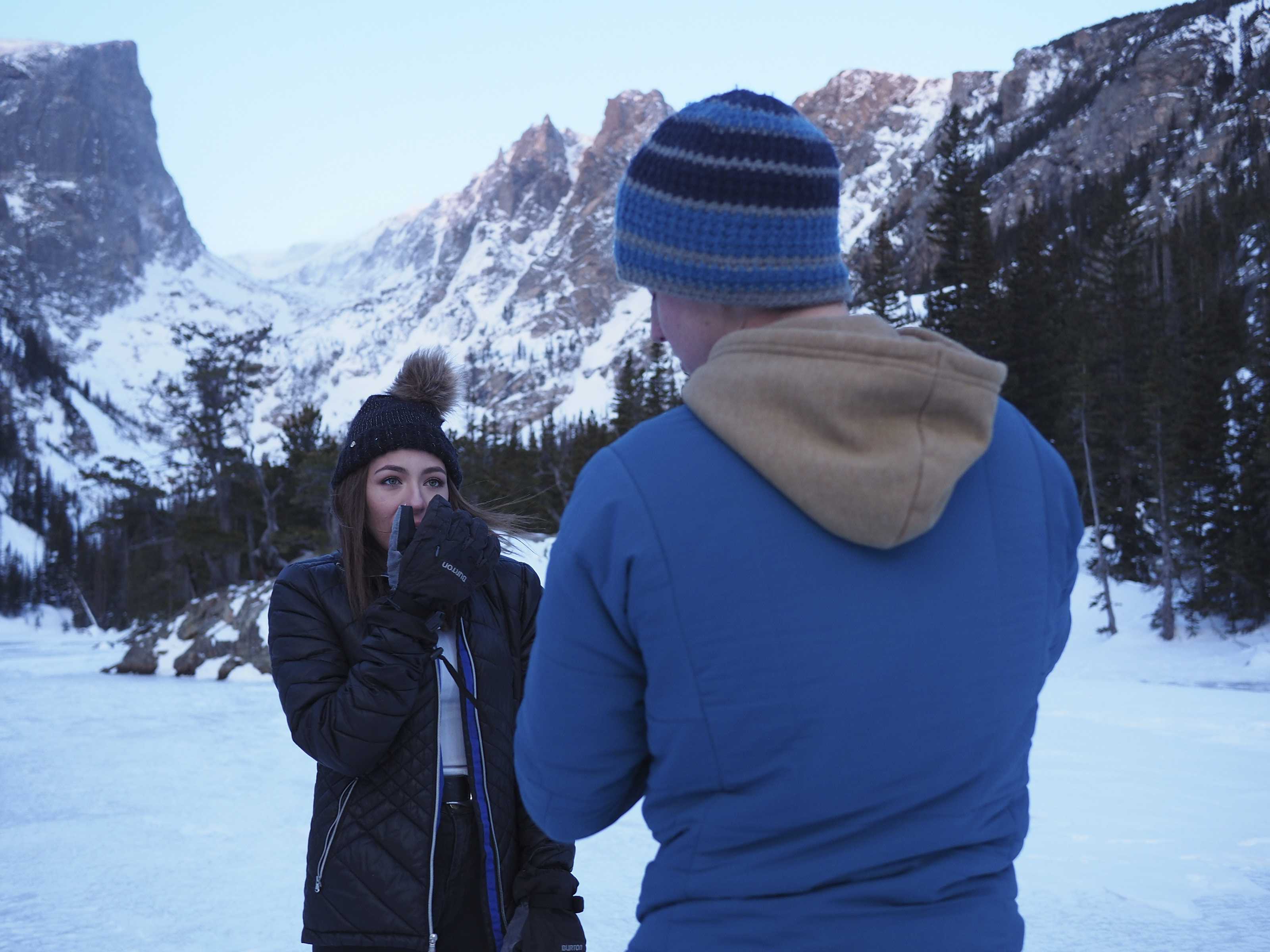 Man takes picture of woman in front of mountain