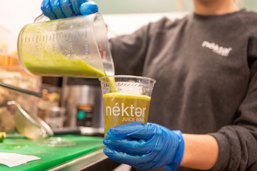 Employee Eryn Coyle pours a juice mix known as the Toxic Flush, composed of parsley, spinach, apple, lemon, and ginger, into a cup behind the counter at Néktar Juice Bar. Opened just over a month ago in Fort Collins, the franchise originated in Texas in 2010. Their mission is to reinvent the juice and smoothie world, similar to the way the coffee industry expanded in the 1990s. (Brooke Buchan | The Collegian)
