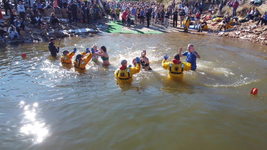 Participants of the Polar Bear Plunge high five larimer dive and rescue members as they dive into the frozen water of Horsetooth Reservoir.  The event took place after a 5k run at Horsetooth. (Devin Cornelius | Collegian)
