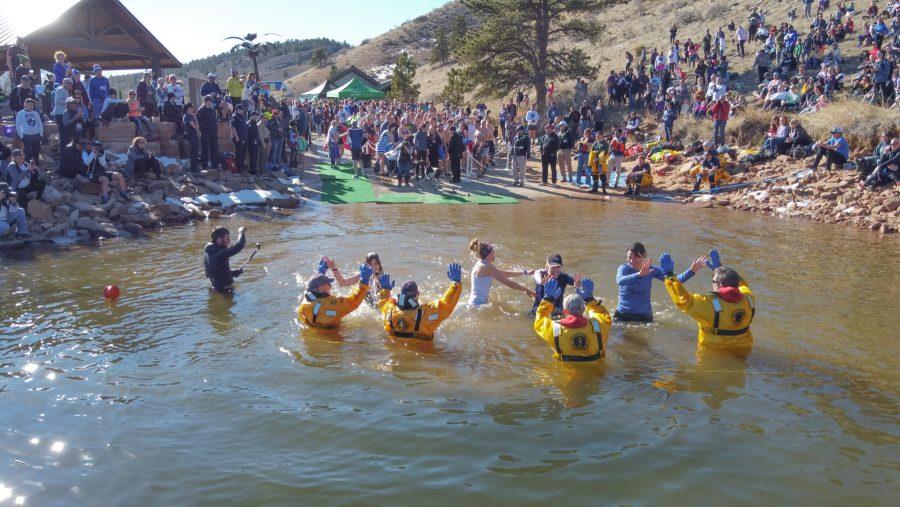 Participants of the Polar Bear Plunge high five Larimer County Dive Rescue Team members as they dive into the partially frozen Horsetooth Reservoir Jan. 25.  The plunge took place after a 5k run along the reservoir. (Devin Cornelius | The Collegian)