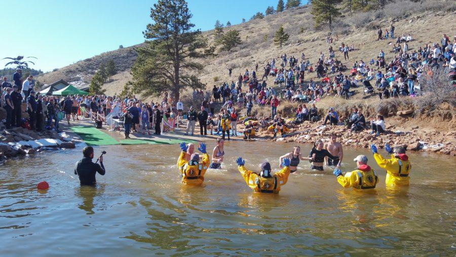 Participants of the Polar Bear Plunge high five larimer dive and rescue members as they dive into the frozen water of Horsetooth Reservoir.  The event took place after a 5k run at Horsetooth. (Devin Cornelius | Collegian)