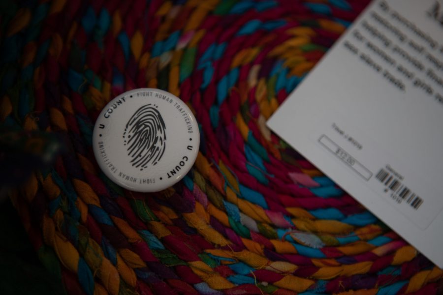 A pin printed with the logo of the sex trafficking prevention organization, U Count, rests on top of colorful products at the Human Trafficking Symposium Thursday, Feb. 6. U Count hosts a marketplace of handmade products from women in countries like India and Spain to make a profit and support themselves after escaping human trafficking. (Brooke Buchan | The Collegian) 